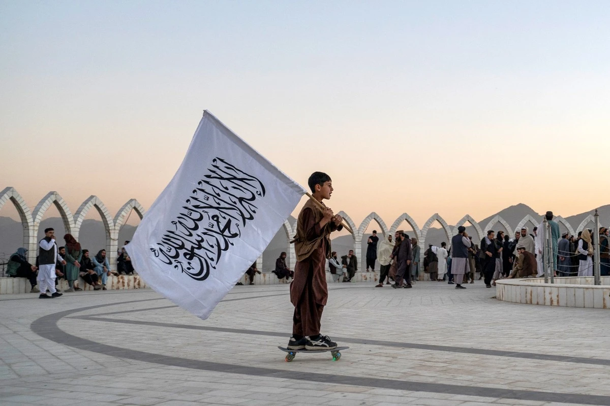 An Afghan boy carries the Taliban flag as he skates across the Wazir Akbar Khan hilltop in Kabul, Oct. 13, 2025. (AFP)