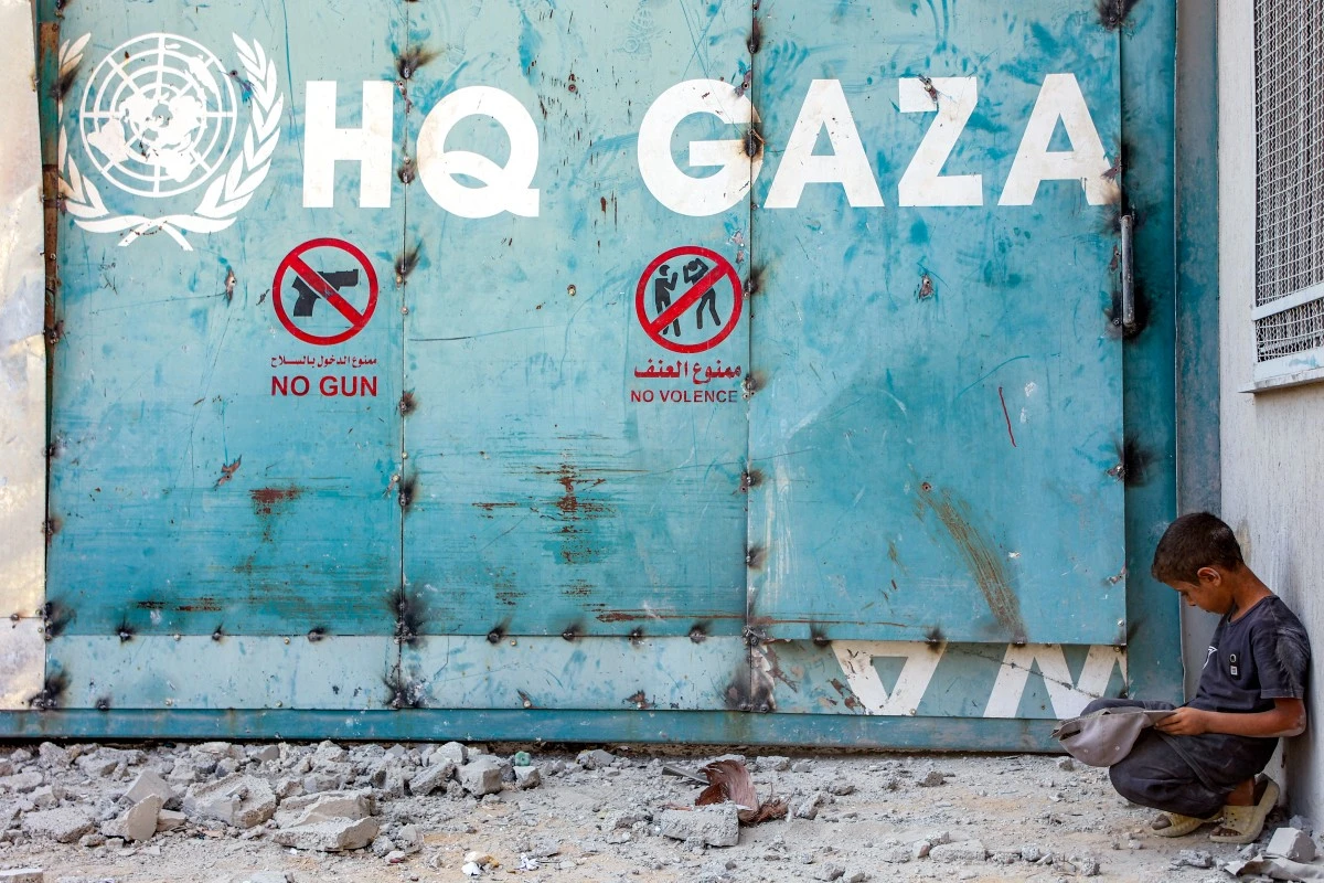 A boy sits outside the entrance to the United Nations Relief and Works Agency for Palestine Refugees (UNRWA) building complex in Gaza City, Sept. 6, 2025. (AFP)