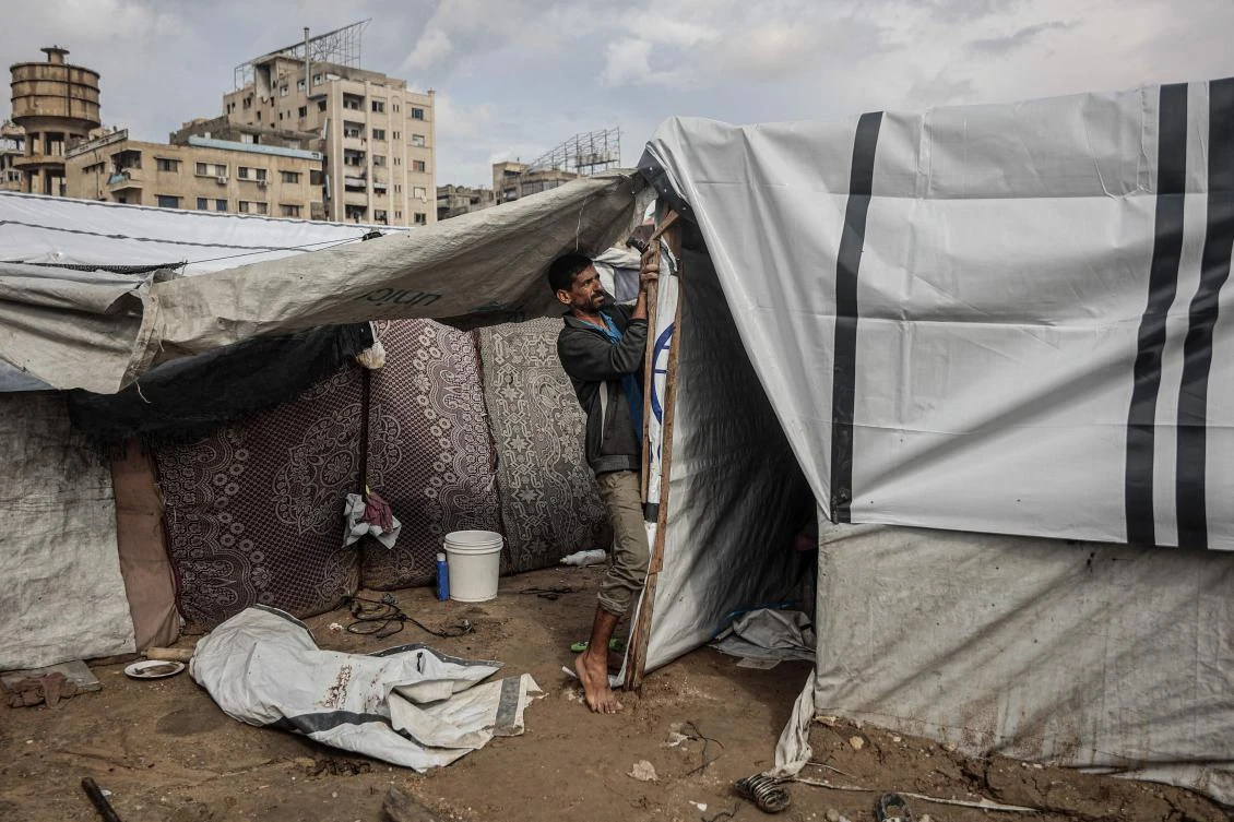 Above, a Palestinian man fixes his makeshift shelter as the first winter rains fall on a displacement camp in Gaza City on Nov. 14, 2025. (AFP)