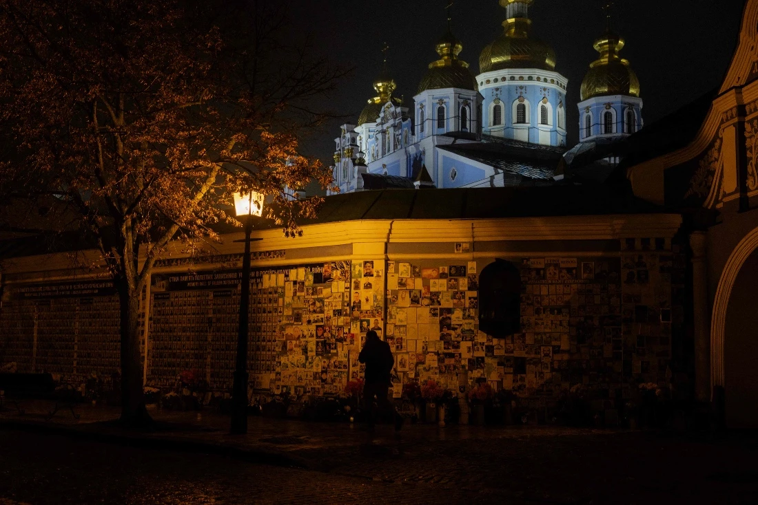 A man walks by the Wall of Remembrance of the Fallen for Ukraine, a memorial dedicated to Ukrainian soldiers during blackout hours in Kyiv, Ukraine. (AFP)