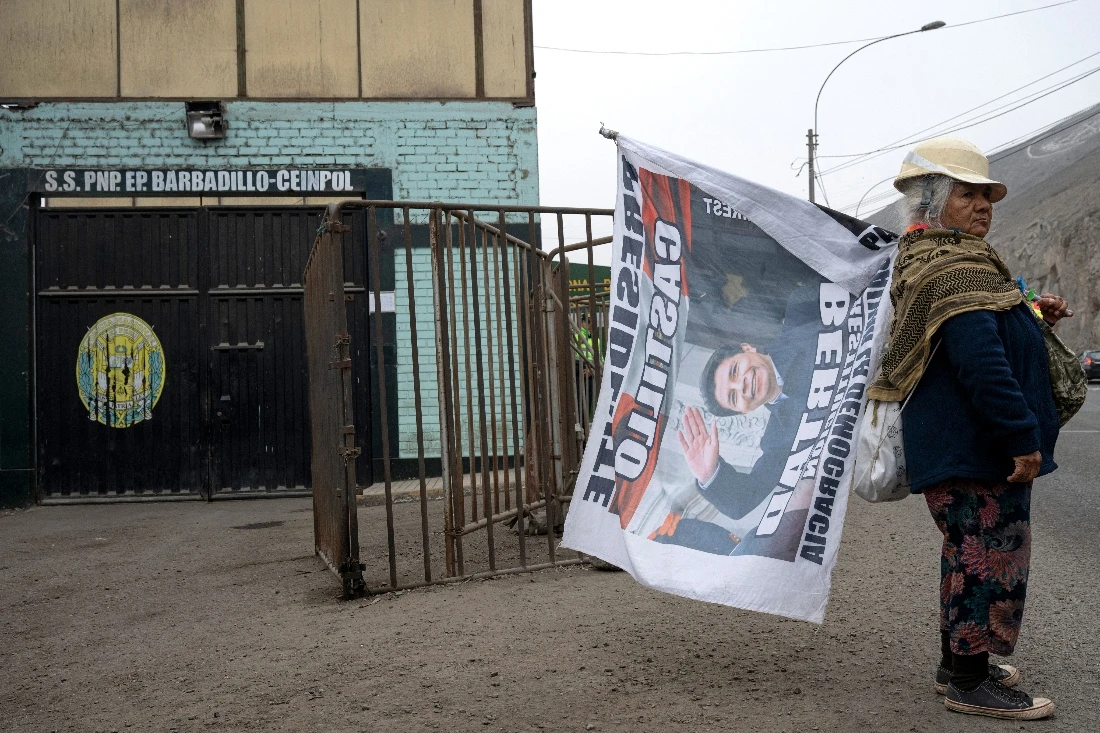 A women holds a flag in support to Peru's former President Pedro Castillo outside the Barbadillo prison in Lima, Peru. (AFP)