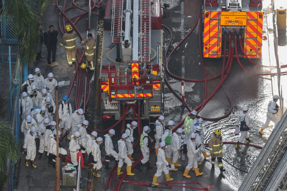 Police officers wearing protective suits walk near the site of a fire-damaged residential block at Wang Fuk Court housing complex in Tai Po, Hong Kong. (Reuters)
