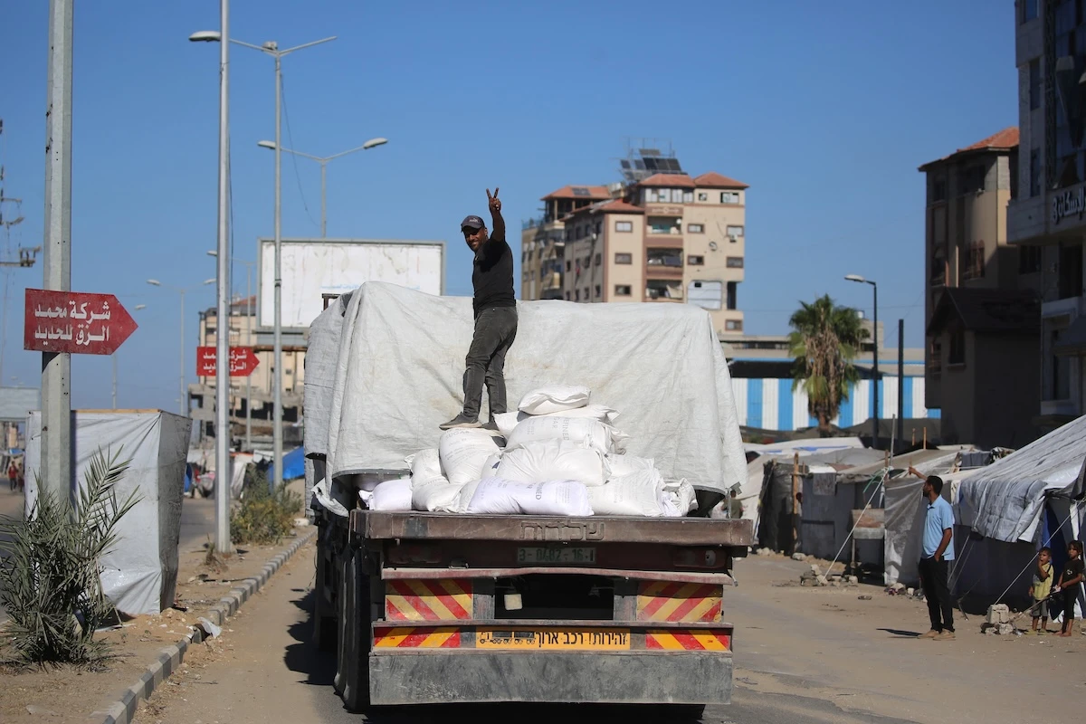 A truck carrying aid which entered Gaza, through the Karm Abu Salem crossing, drive past displacement tents at the Nuseirat refugee camp in the central Gaza Strip on Oct. 14, 2025. (AFP file photo)