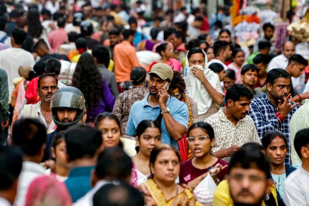 A man speaks on a mobile phone as he walks through a crowded market in Varanasi, India, on Oct. 25, 2025. (AFP)