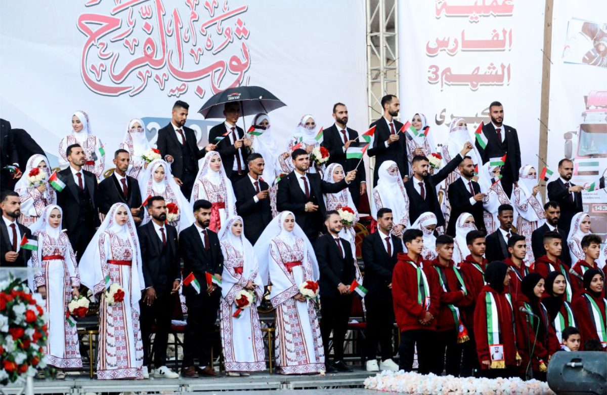 Some of the 54 brides and grooms gather on a stage during a mass wedding dubbed the "The Dress of Joy", organised by the Al-Fares Al-Shahm Foundation, in Khan Yunis, southern Gaza Strip on December 2, 2025. (AFP)