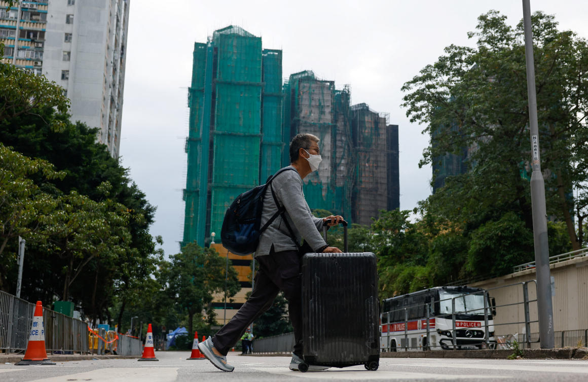 A resident of Wang Chi House, the only block in the complex not destroyed by the 40-hour inferno, rolls his suitcase across the road after fetching his belongings, in Tai Po, Hong Kong on Dec. 3, 2025. (Reuters)