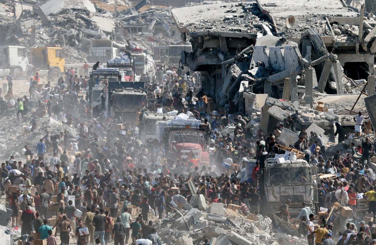 Palestinians collect aid supplies from trucks in Khan Younis, southern Gaza Strip, on October 12, 2025, amid a ceasefire between Israel and Hamas. (REUTERS)
