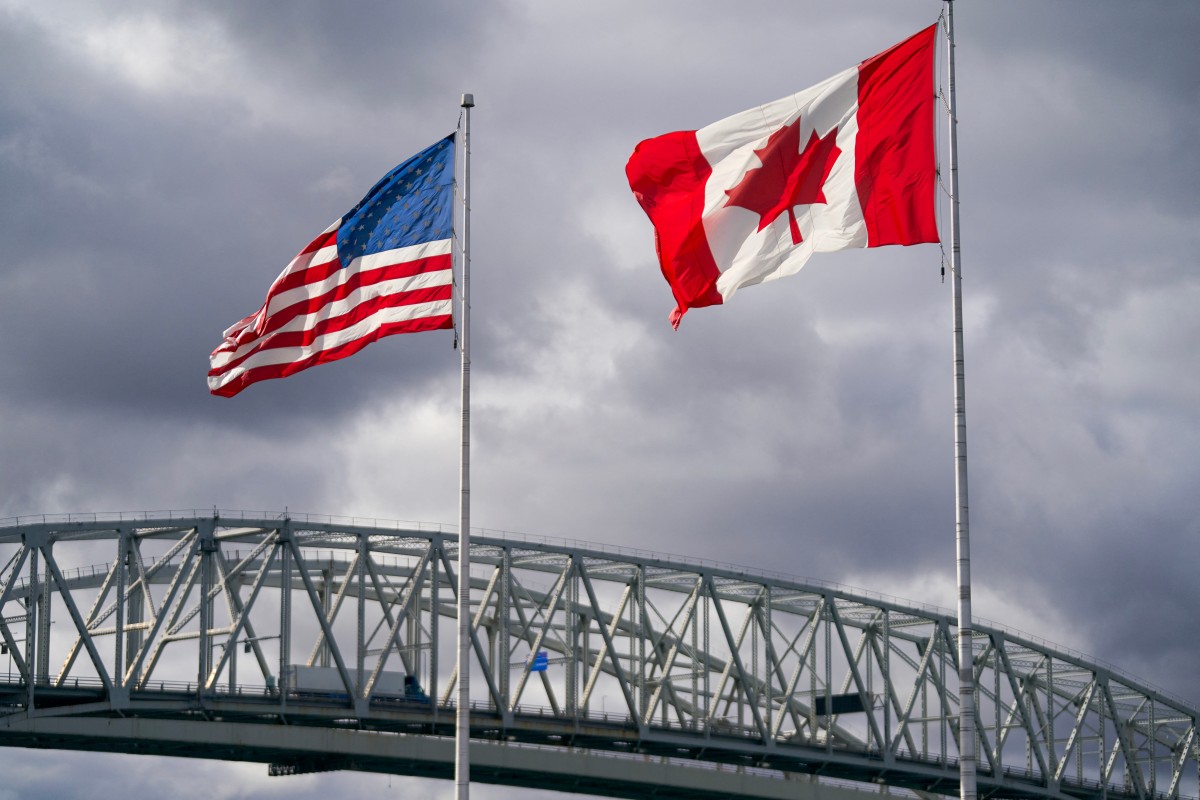 The US and Canada flags flutter next to the Blue Water Bridge border crossing in Point Edward, Ontario, Oct. 24, 2025. (AFP)