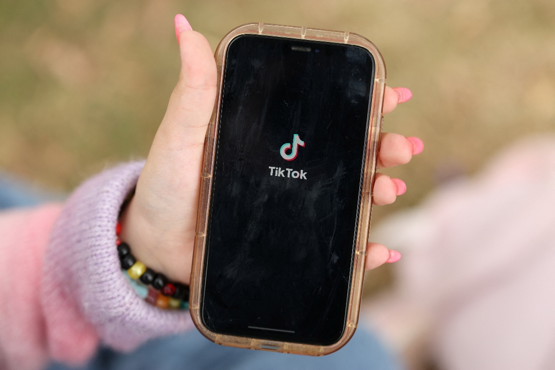 A girl poses while opening the TikTok app on her phone in Sydney, Australia. (Reuters)