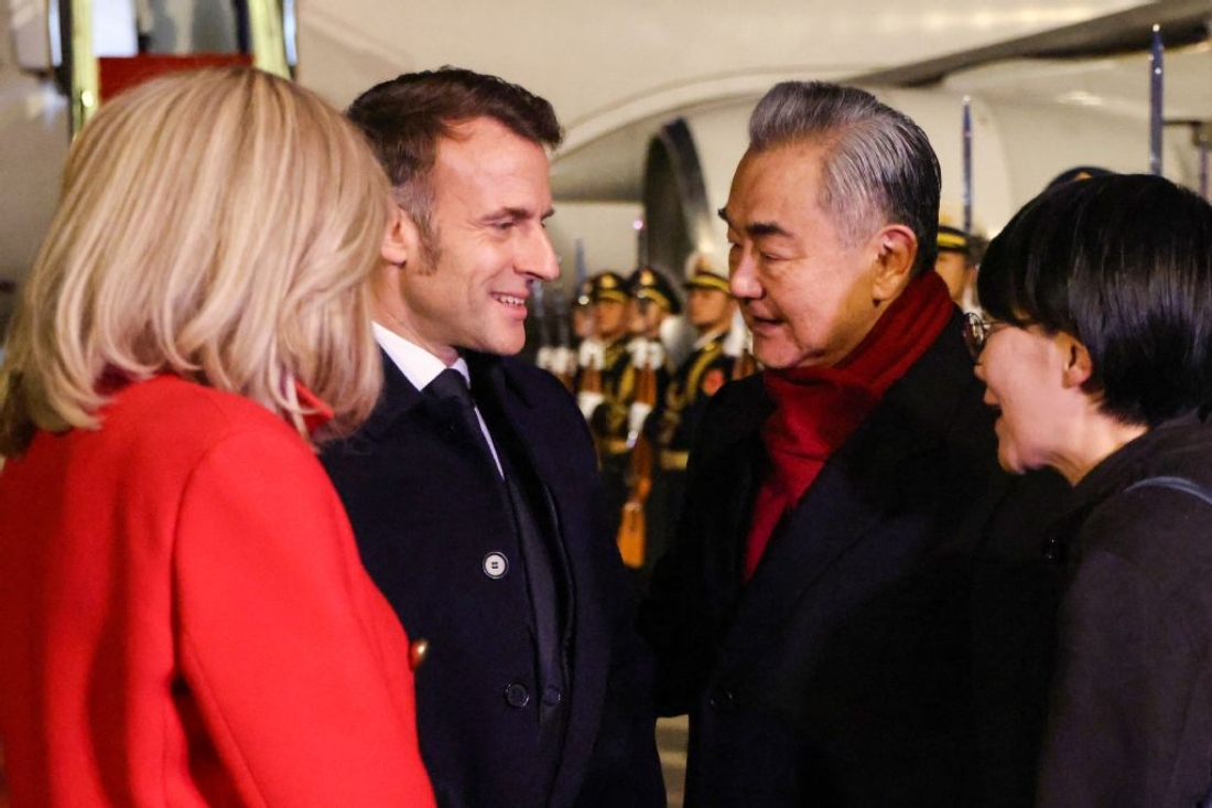 China's Foreign Minister Wang Yi receives France's President Emmanuel Macron and his wife Brigitte Macron upon their arrival at the Capital International Airport in Beijing, China. (AFP)