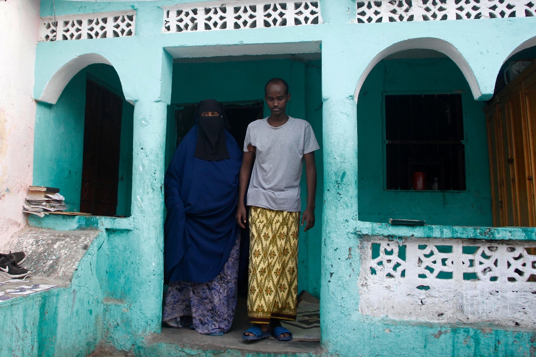 Mohamed Abdi Awale, who says he was tortured by smugglers while trying to reach Europe, is helped by his mother at their home in Mogadishu, Somalia. (AP)
