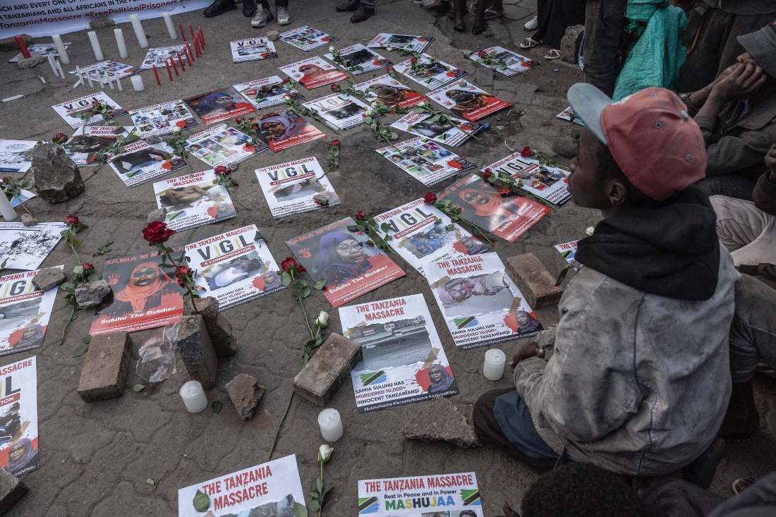 A street boy sits next to roses and placards showing portraits of Tanzanian President Samia Suluhu Hassan during a memorial vigil to honour Tanzanians killed during post-election unrest in Nairobi. (AFP)