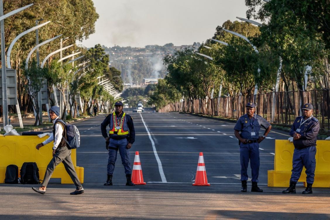 A pupil crosses a road as South African Police Service (SAPS) officers monitor the area near the Nasrec Expo Centre in Johannesburg on November 22, 2025, ahead of the opening of the G20 Leaders’ Summit. (AFP)