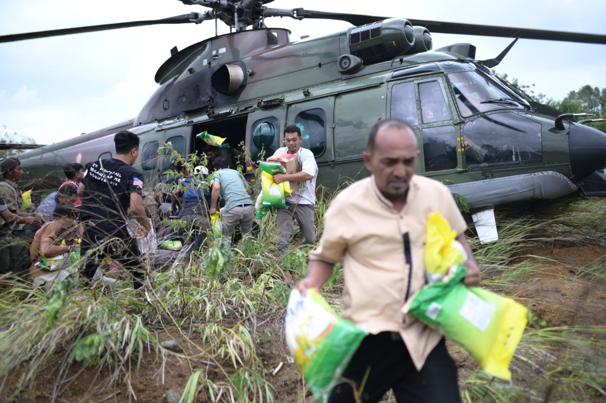 Flood survivors carry relief goods distributed by an Indonesian Air Force helicopter in Central Aceh, Indonesia, on Dec. 6, 2025. (AP Photo/Reza Saifullah)