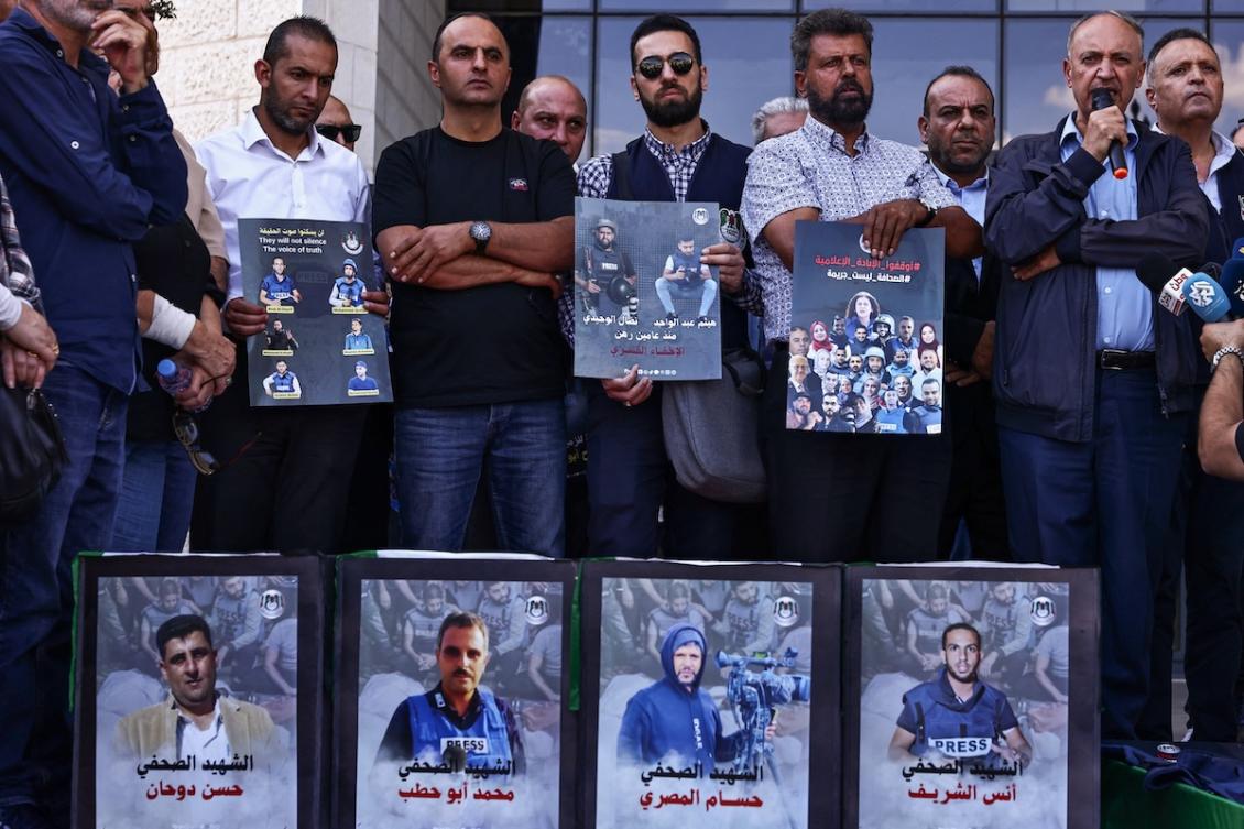 Palestinian journalists and local officials lift portraits of media workers killed in Israeli fire in Ramallah city in the occupied West Bank on Oct. 8, 2025. (AFP)