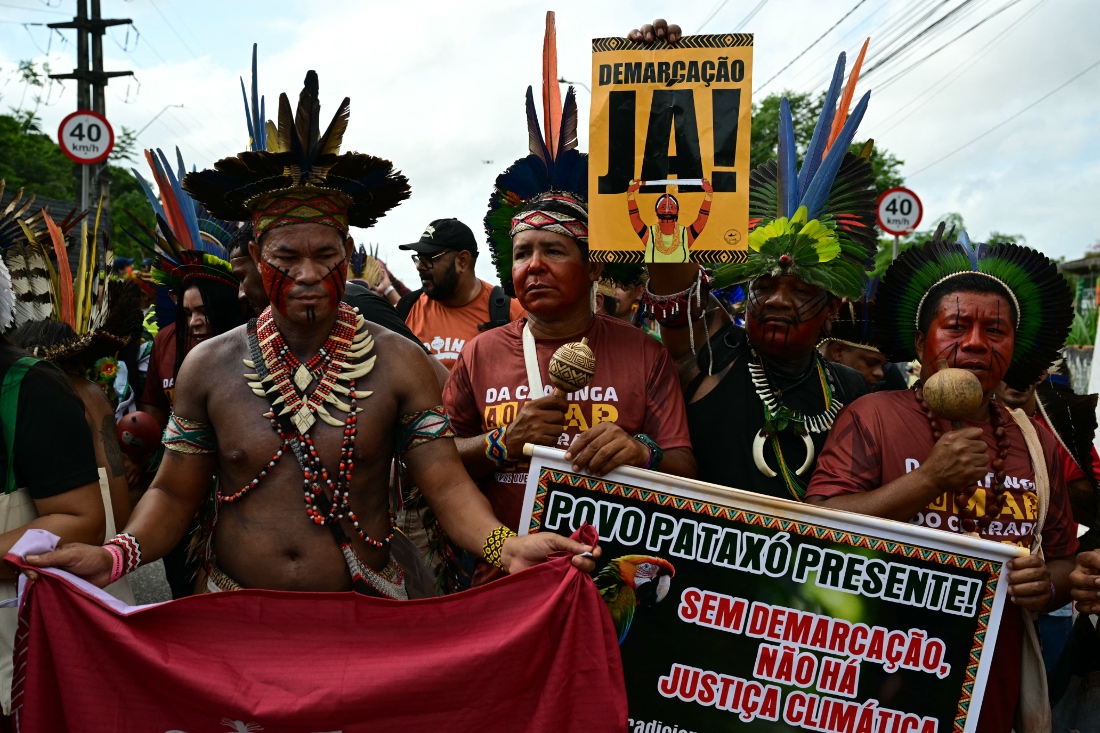 Indigenous people take part in a demonstration called "Indigenous People Global March" with a sign reading "Demarcation Now!" in Belem, Brazil. (AFP)