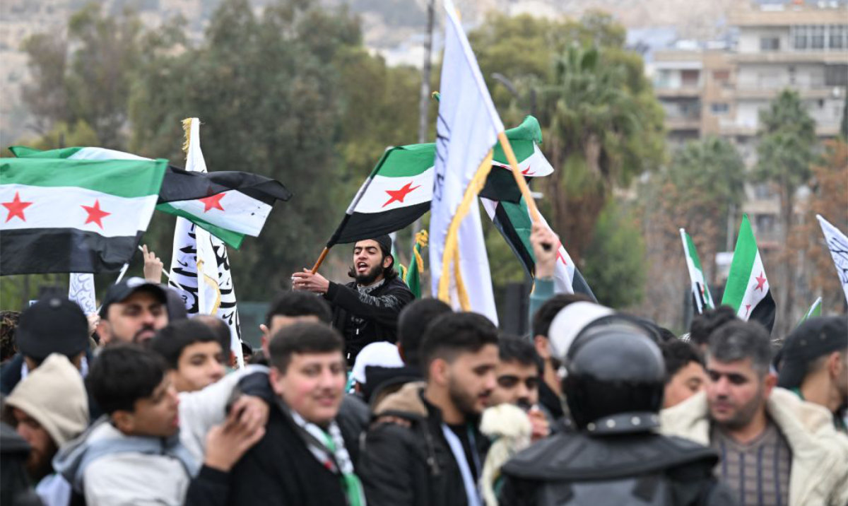 People wave Syrian flags as they celebrate a year since the ousting of longtime ruler Bashar Al-Assad in Damascus, on December 8, 2025. (AFP)
