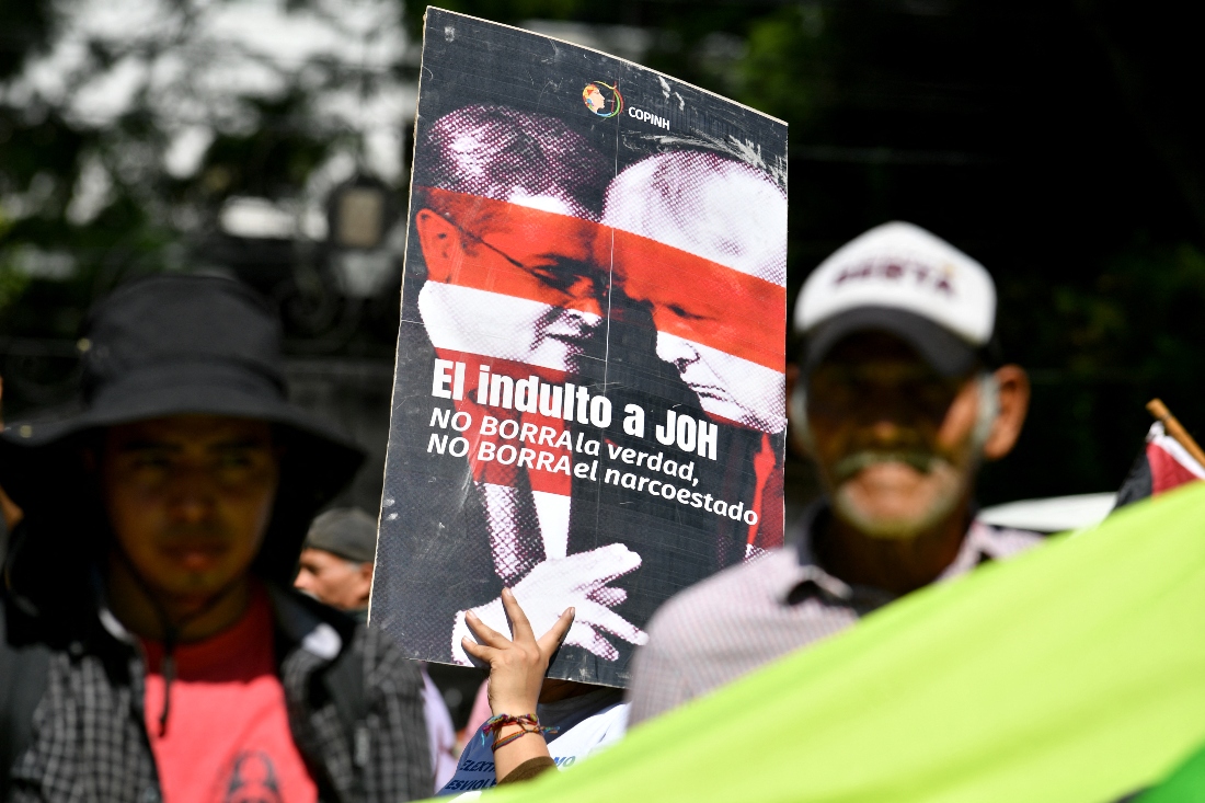 A woman holds a banner reading “The pardon for Juan Orlando Hernandez (JOH) does not erase the truth, does not erase the narco-state,” during a protest outside the U.S. Embassy in Tegucigalpa, Honduras. (AFP)