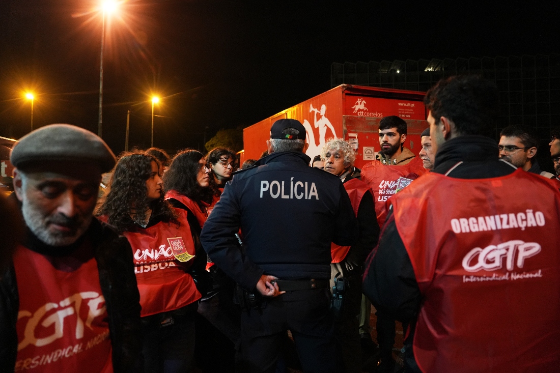 A police officer negotiates with striking workers blocking the movement of trucks at the gate to warehouses of the Portuguese postal services company in Lisbon, Portugal. (AP)
