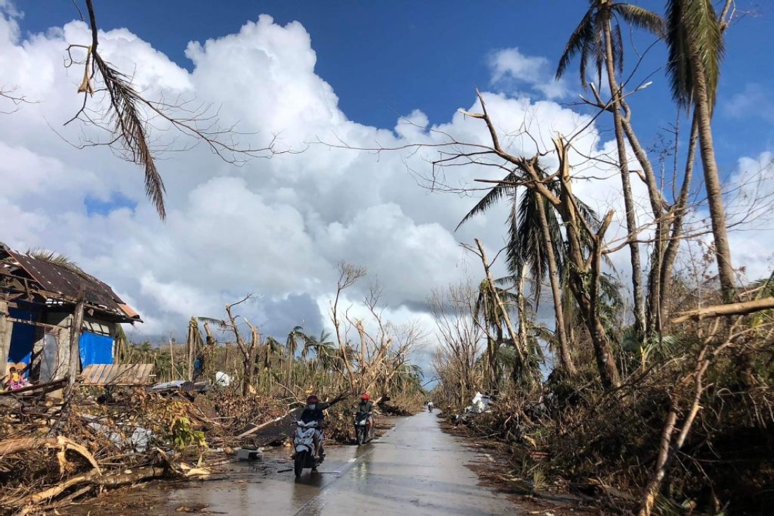 A photo shows shows motorists speeding past fallen coconut trees at the height of Super Typhoon Rai along a highway in Del Carmen town in the Philippines. (AFP)