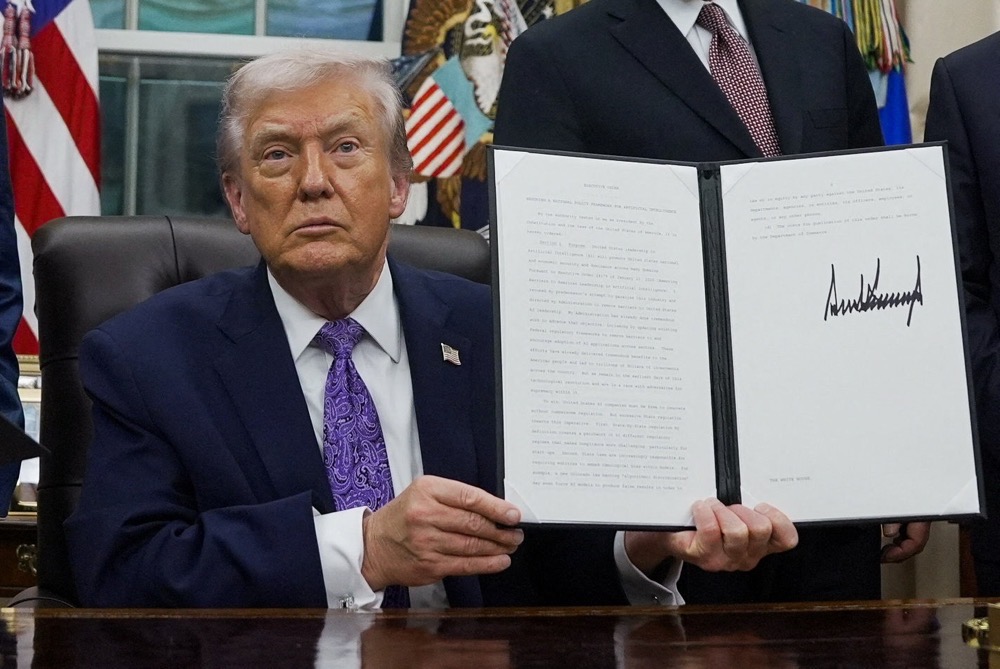 President Donald Trump shows a signed executive order on AI in the Oval Office at the White House, in Washington, D.C., U.S. December 11, 2025. (Reuters)()