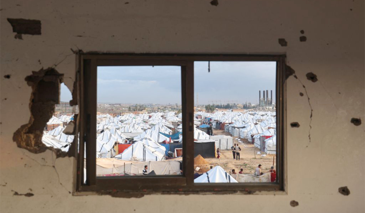Palestinians stand outside a 'tent city' housing displaced Palestinians who lost their homes in the Gaza war, following heavy rains in the Nuseirat refugee camp in the central Gaza Strip, on December 13, 2025. (AFP)