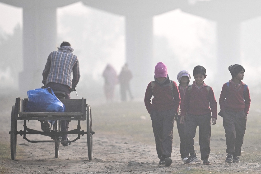 Schoolchildren walk through a field on a smoggy winter morning in New Delhi, India. (AFP)
