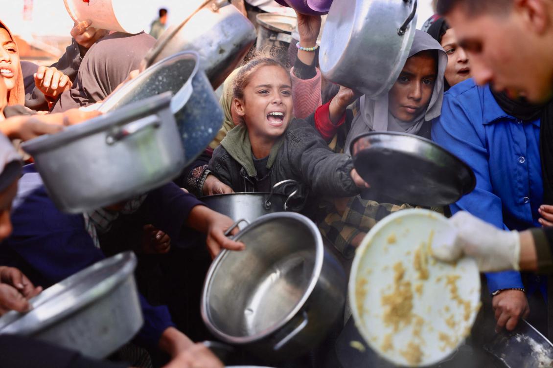 Displaced Palestinians gather to receive donated food portions at a charity kitchen in Khan Yunis in the southern Gaza Strip Wednesday. The US-sponsored ceasefire, in effect since Oct. 10 remains fragile. (AFP)