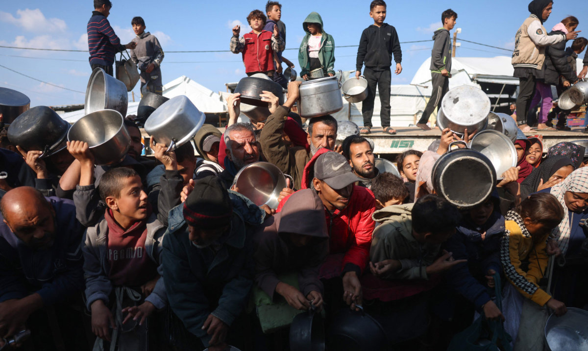 Displaced Palestinians gather to receive donated food portions at a charity kitchen in Khan Yunis in the southern Gaza Strip on December 17, 2025. (AFP)