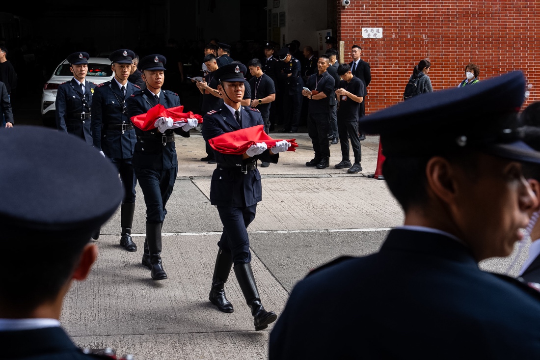 Firefighters carry Hong Kong SAR flags outside a funeral parlor to pay tribute to Ho Wai-ho, the firefighter who lost his life in the line of duty during the deadly fire at Wang Fuk Court, Hong Kong. (AP)