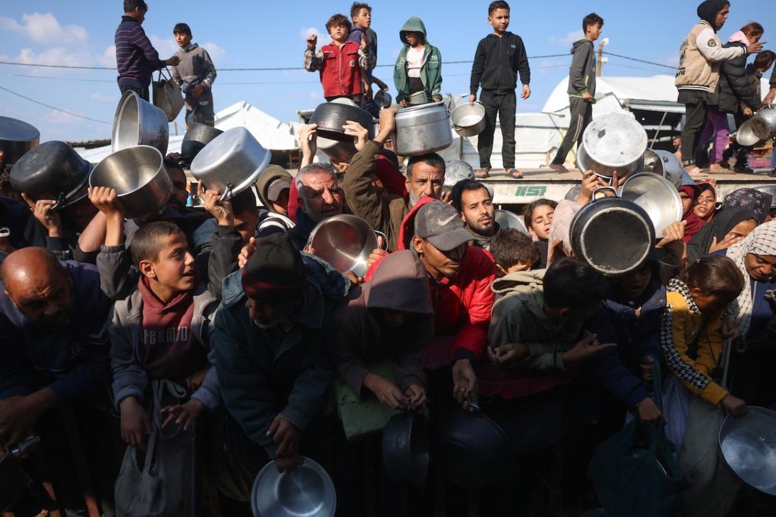 Displaced Palestinians gather to receive donated food portions at a charity kitchen in Khan Yunis in the southern Gaza Strip on December 17, 2025. (FILE/AFP)