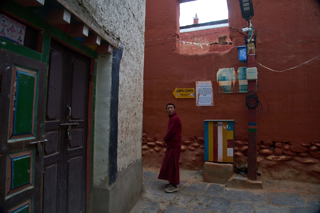 A Buddhist monk walks in an alley as a CCTV camera mounted on a pole watches over the area in the ancient ethnic Tibetan city of Mustang, Nepal. (AP)