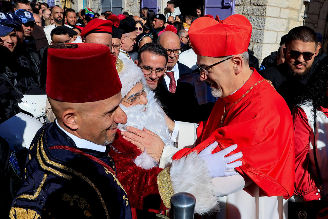 Cardinal Pierbattista Pizzaballa, Latin Patriarch of Jerusalem, greets a Palestinian, who is dressed as Santa Claus on Christmas Eve, in the Old City of Bethlehem in the Israeli-occupied West Bank. (Reuters)