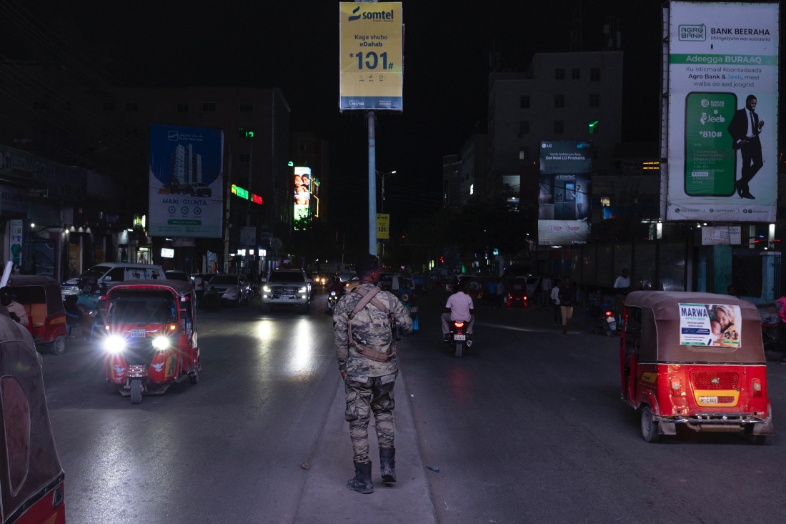 A Somali police officer patrols along a busy street at night in Mogadishu, Somalia. (AFP)
