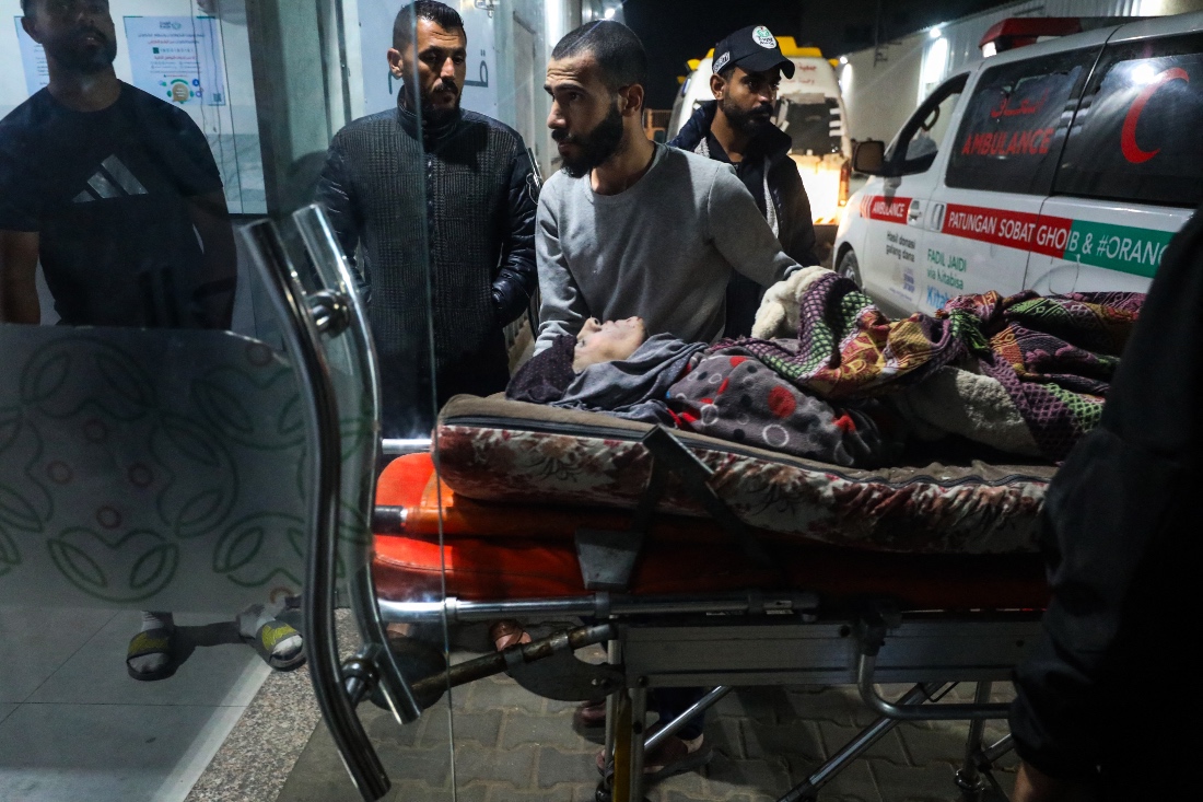 People bring a person wounded in an Israeli strike to Al-Awda hospital in Nuseirat, in the central Gaza Strip. (AFP)