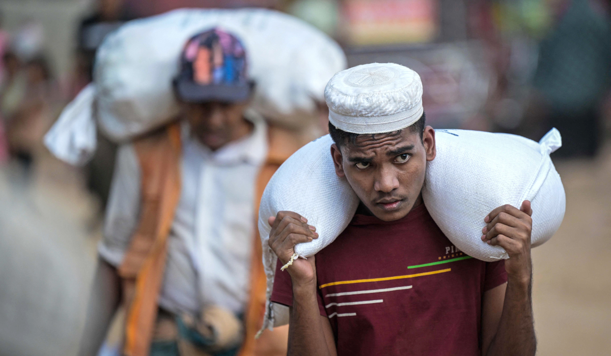 A Rohingya refugee carrying relief materials after collecting them from a distribution point at the Kutupalong refugee camp in Bangladesh's Ukhia. (AFP)