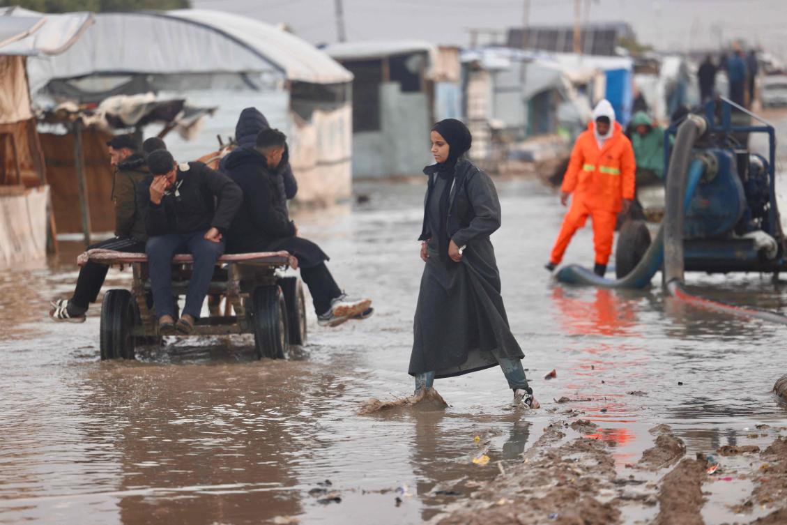 A displaced Palestinian woman walks through floodwaters in Al-Mawasi refuge camp in the southern Gaza Strip as the region experiences cold winter conditions. (AFP)