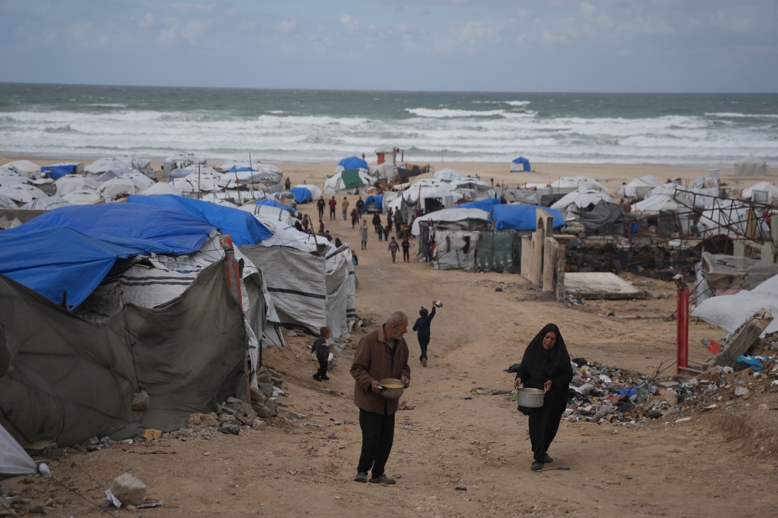Palestinians receive donated food at a temporary camp for displaced people, on the beach near the port of Gaza City. (AP)