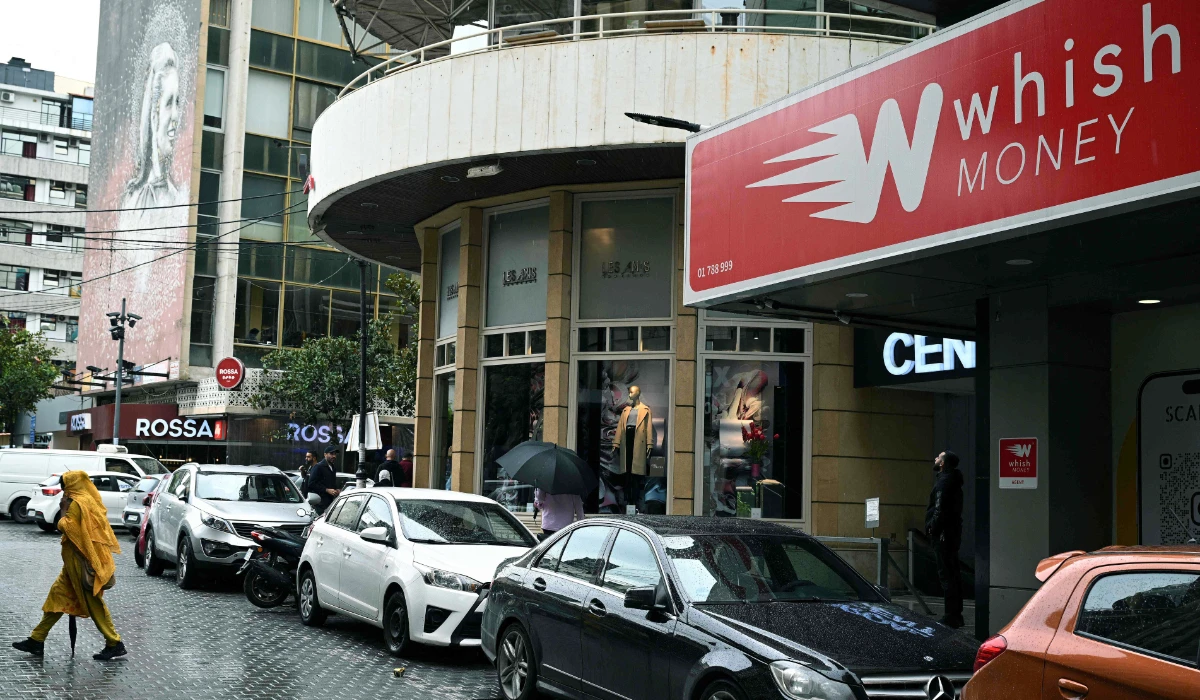 A woman walks past a money transfer company office in Beirut on November 14, 2025. (AFP)