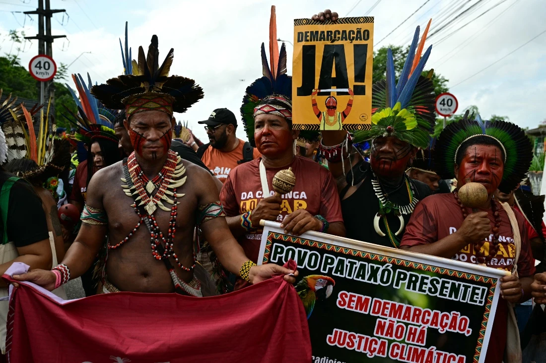 Indigenous people take part in a demonstration called "Indigenous People Global March" with a sign reading "Demarcation Now!" in Belem, Brazil. (AFP)