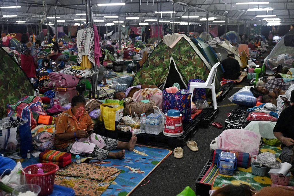 Displaced residents rest at an evacuation center at Chang International Circuit in the Thai border province of Buriram on Dec. 12, 2025. (AFP)