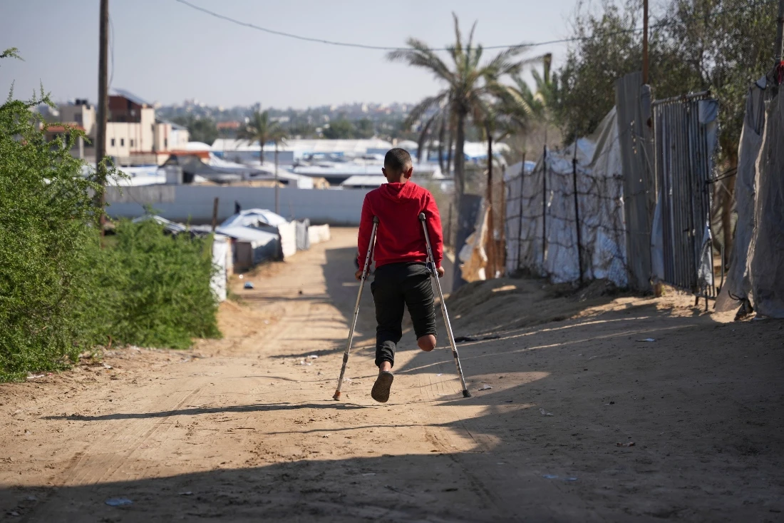 Fadi al-Balbisi, 12, whose right leg was amputated after a shell fired by the Israeli army, walks on crutches back home after receiving rehabilitation training with a prosthetic leg at Hamad Hospital in Zawaida, central Gaza Strip. (AP)