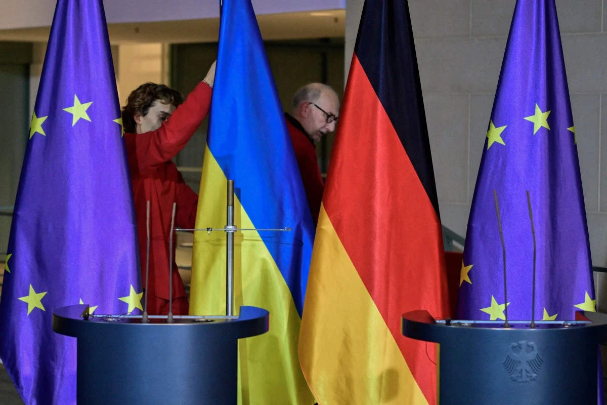 Workers install the Ukrainian and the German flag ahead of a press conference of the German Chancellor and Ukraine’s President at the Chancellery in Berlin, Dec. 15, 2025. (AFP)