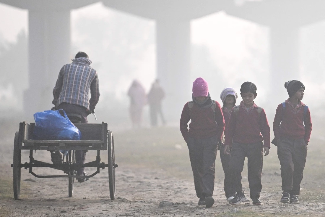 Schoolchildren walk through a field on a smoggy winter morning in New Delhi, India. (AFP)