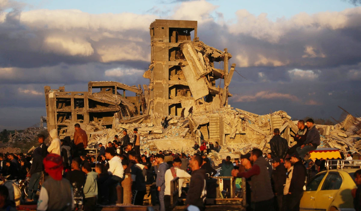 Displaced Palestinians stand next to destroyed houses in Nuseirat camp in the central Gaza Strip on December 19, 2025. (AFP)