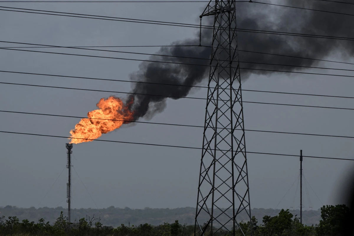 The flame from a chimney at an oil refinery is seen along the highway between El Furrial and Maturin in Monagas state, Venezuela, April 7, 2023. (AFP)