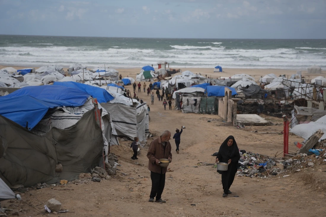 Palestinians receive donated food at a temporary camp for displaced people, on the beach near the port of Gaza City. (AP)