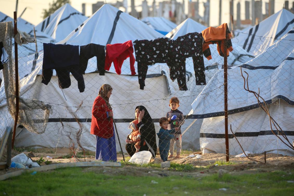 Palestinians stand outisde makeshift shelters in the Nuseirat refugee camp in the central Gaza Strip on December 31, 2025. (AFP)