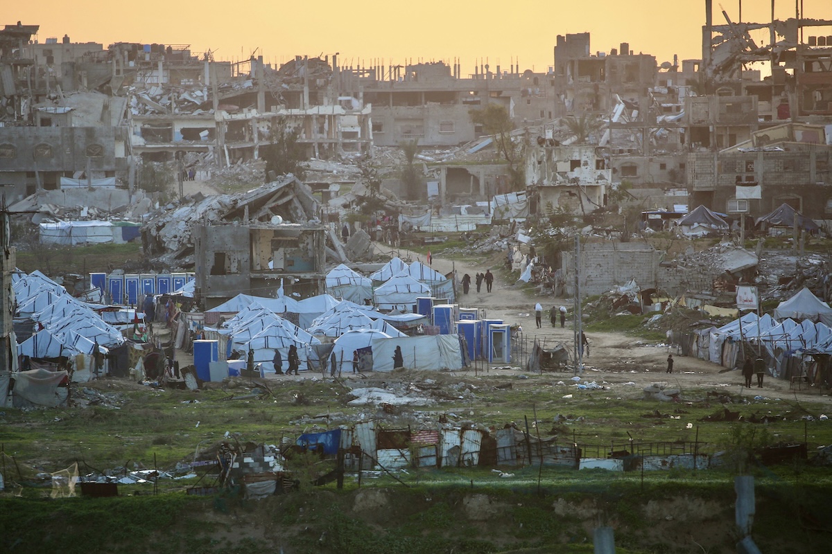 Palestinians walk past destroyed buildings in the Nuseirat refugee camp in the central Gaza Strip on December 31, 2025. (FILE/AFP)