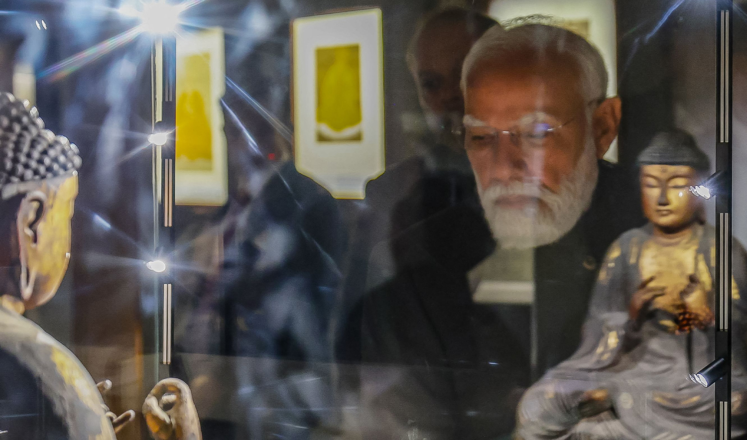 This photograph taken and released by the Indian Press Information Bureau (PIB) on January 3, 2026 shows India's Prime Minister Narendra Modi looking at a sculpture of the Buddha during an exhibition in New Delhi. (PIB/AFP)